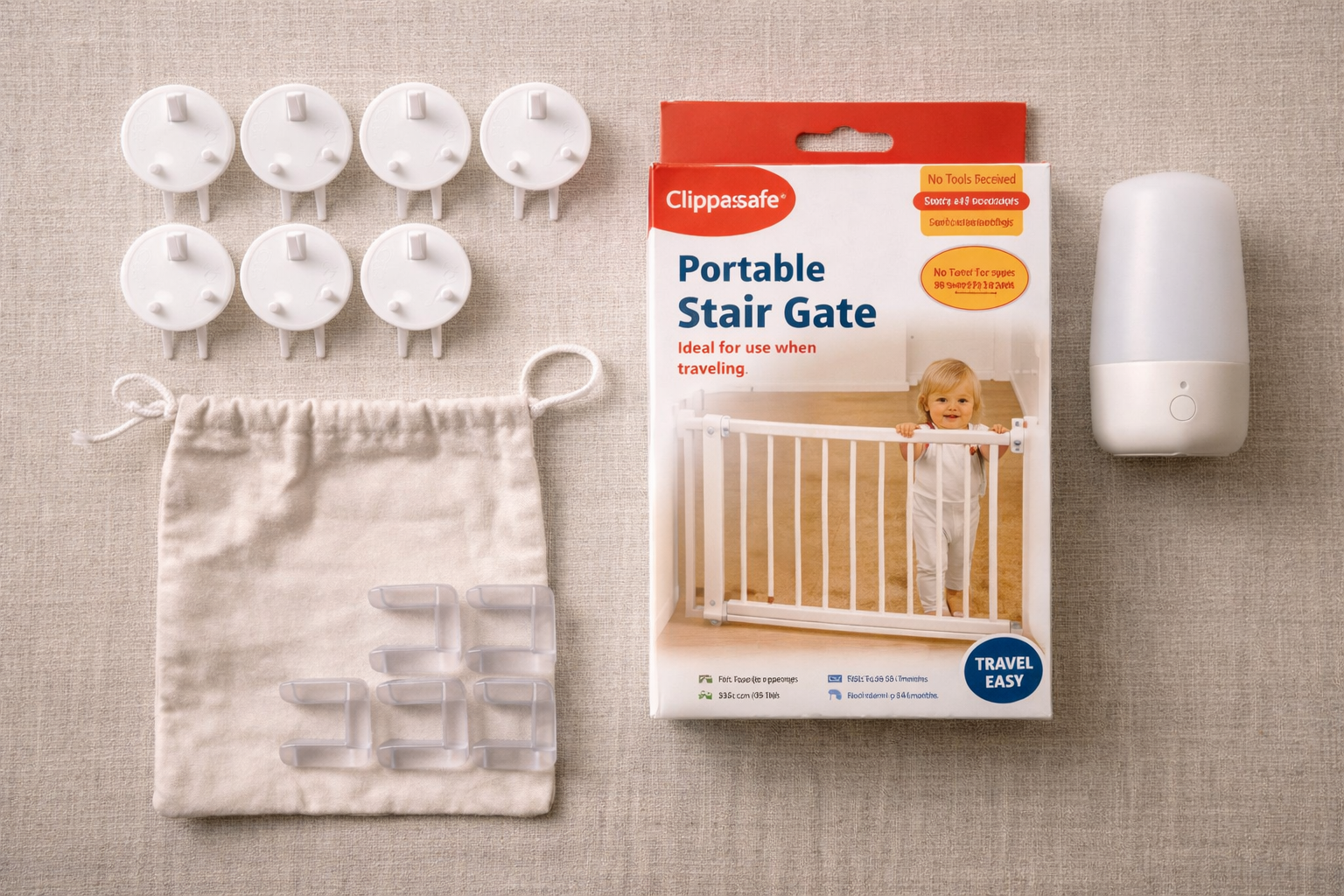 A flat-lay of a simple baby-proofing travel kit — socket covers, a portable stair gate box, a plug-in nightlight, and a door wedge laid out neatly on a wooden surface