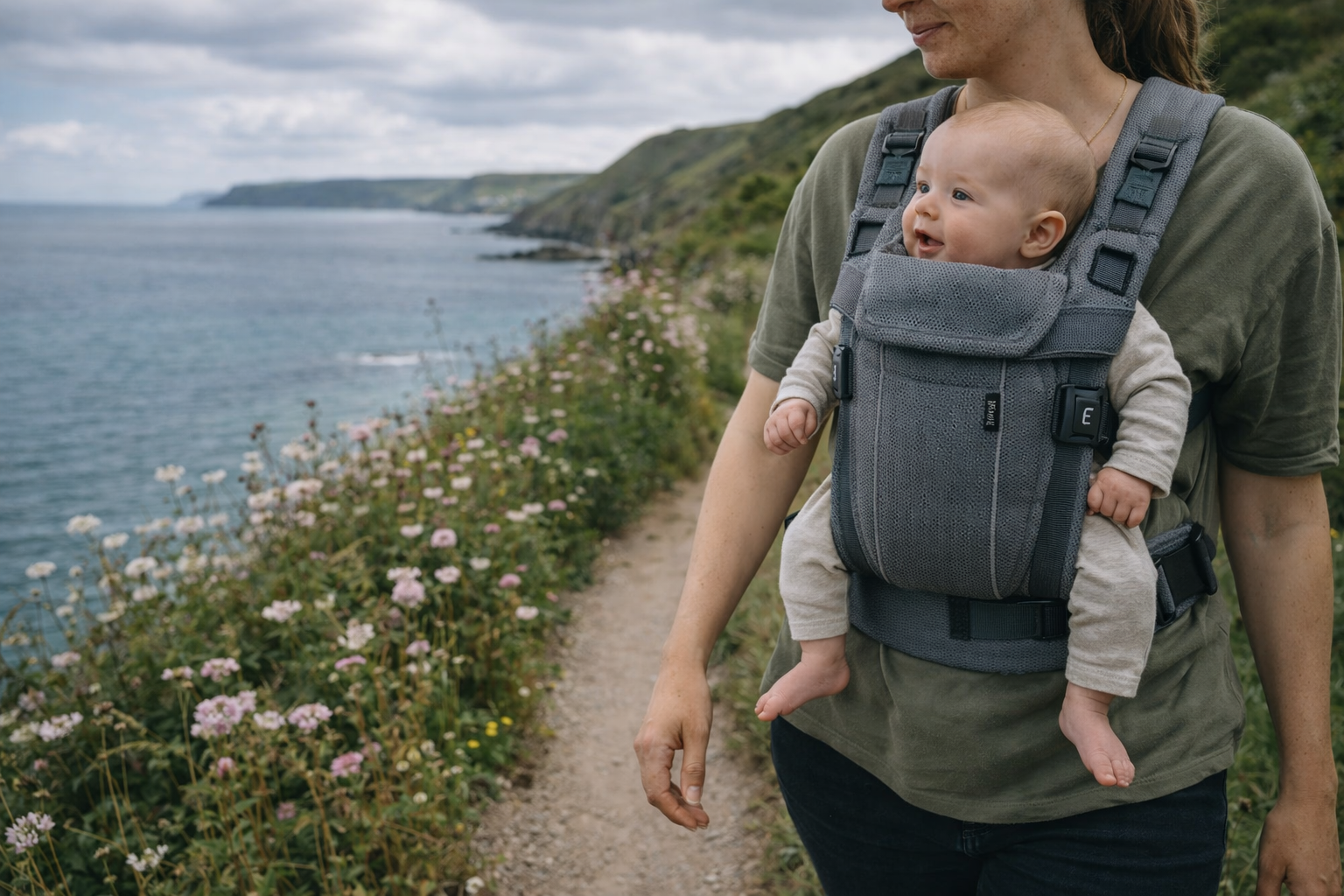 Parent wearing an ergonomic baby carrier while on a UK day trip with baby, walking through a park